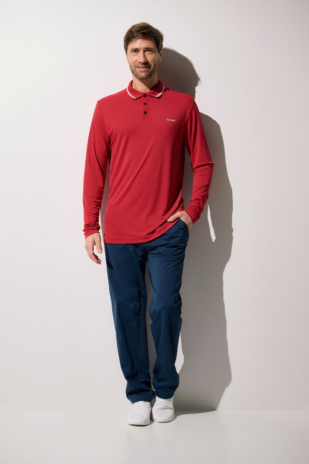 Homme portant un polo anti-UV rouge Augusta, manches longues, UPF 50+, parfait pour le golf.