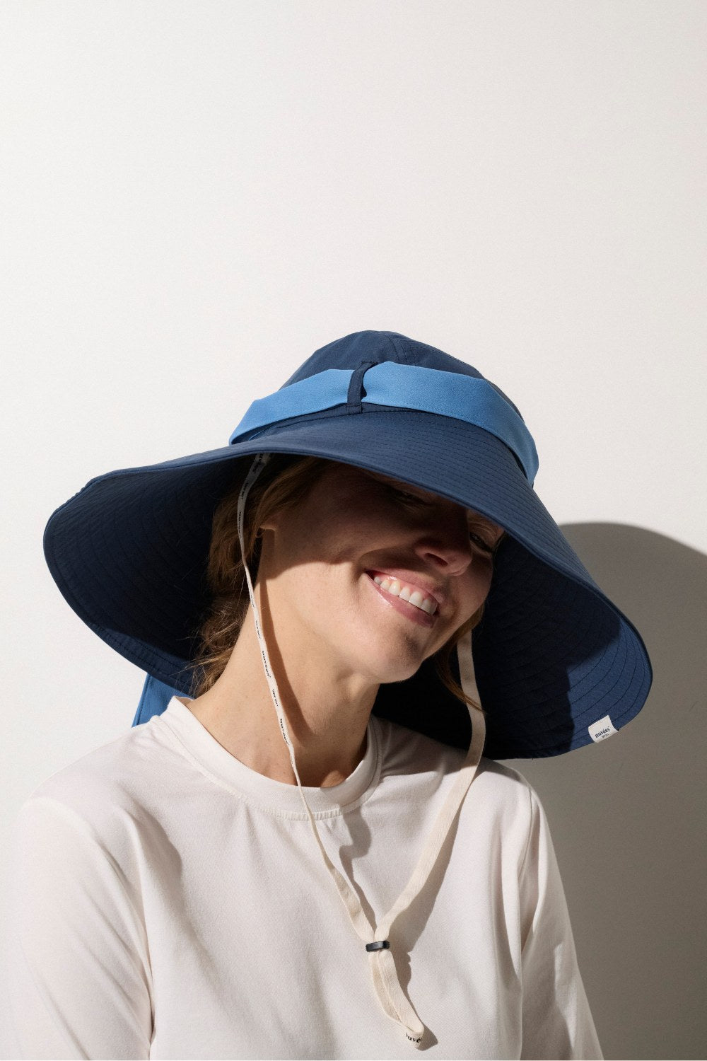 Femme portant un t-shirt anti-UV à manches longues et un chapeau large pour protection solaire.