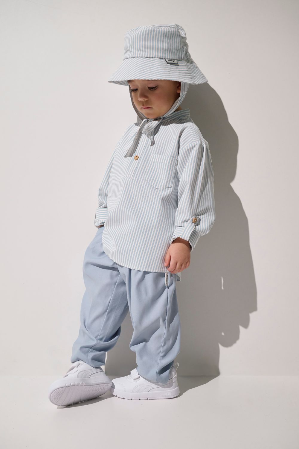 Chemise anti-UV Sylt pour enfant, rayée bleue et blanche, légère, avec chapeau, idéale pour les journées ensoleillées.