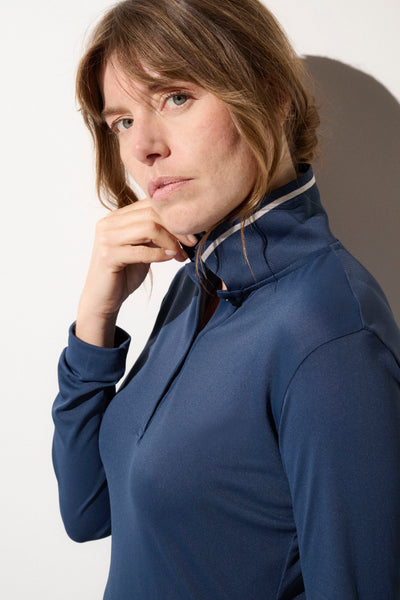 Femme portant un polo anti-UV bleu, respirant et léger, offrant protection solaire avec UPF 50+.