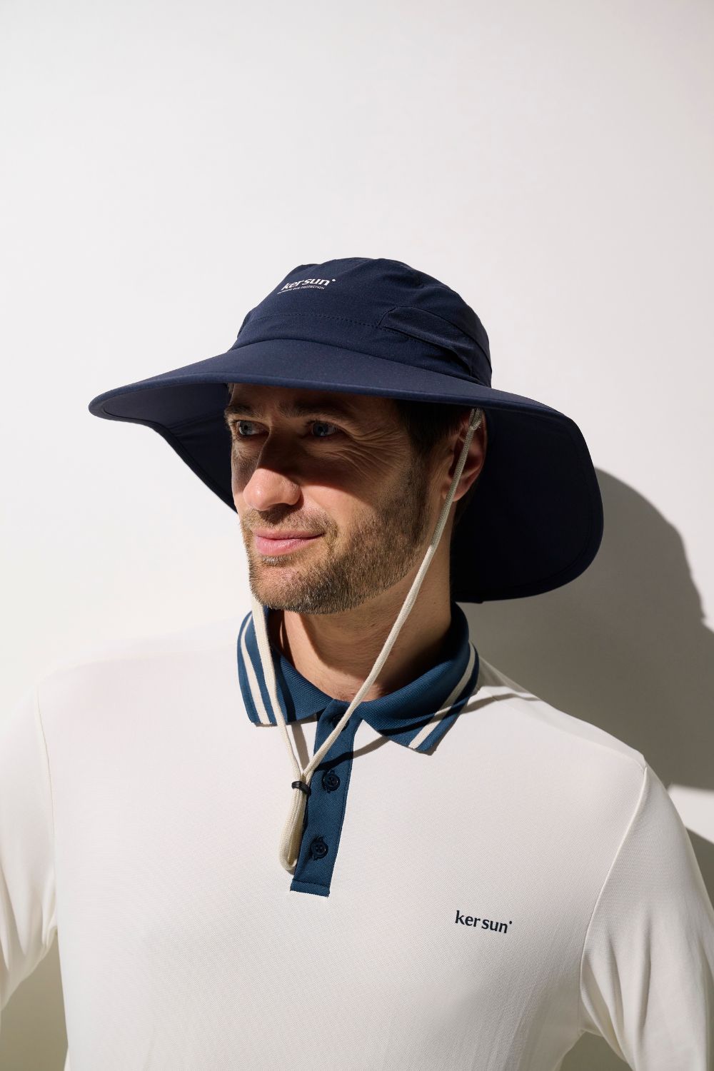 Homme portant un polo anti-UV - Augusta de Ker Sun avec un chapeau à large bord, idéal pour le soleil.