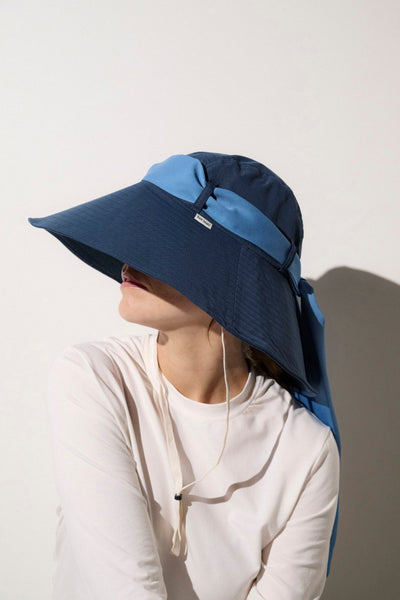 Femme portant un chapeau anti-UV bleu avec un ruban bleu clair. Idéal pour une protection efficace contre les rayons du soleil.