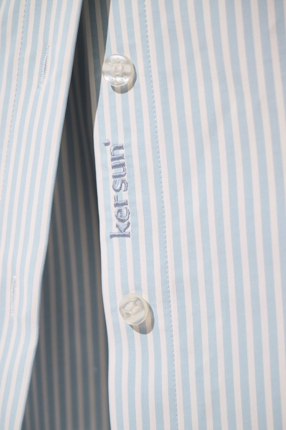 Chemise longue anti-UV - Sylt de Ker Sun, tissu léger à rayures bleu clair, boutons élégants pour une protection solaire.