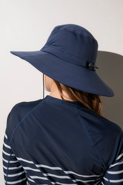 Chapeau de bain anti-UV bleu marine UPF 50+ porté par une femme, idéal pour les activités sous le soleil.