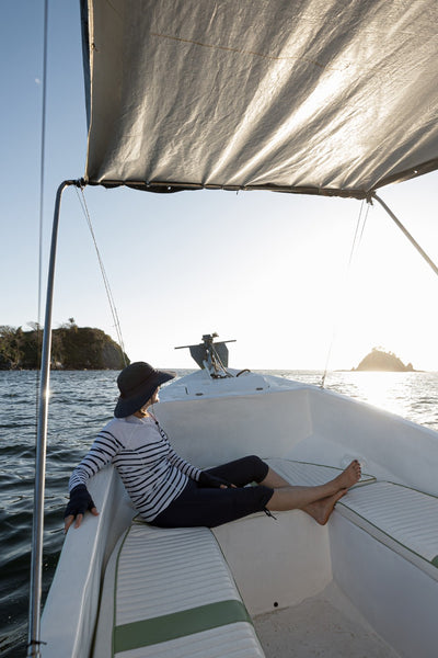 Femme en t-shirt de bain anti-UV Moorea, UPF 50+, se détendant sur un bateau au soleil.