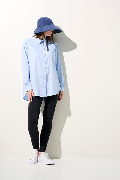 Femme portant un legging anti-UV - Antibes avec une chemise bleu clair, chapeau, pour une protection solaire élégante.