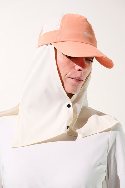 Femme portant une casquette anti-UV bicolore avec protection solaire, idéale pour activités extérieures.