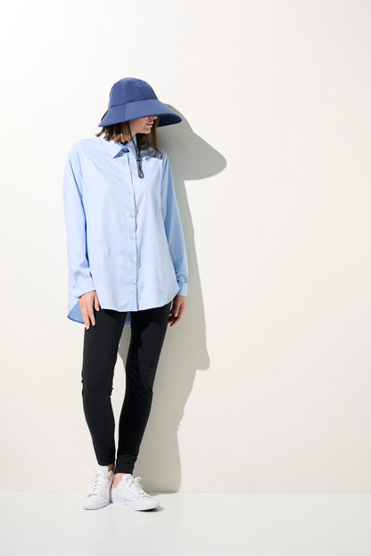 Femme portant un chapeau anti-UV - Capri bleu, chemise légère et pantalon noir, idéale pour la protection solaire.