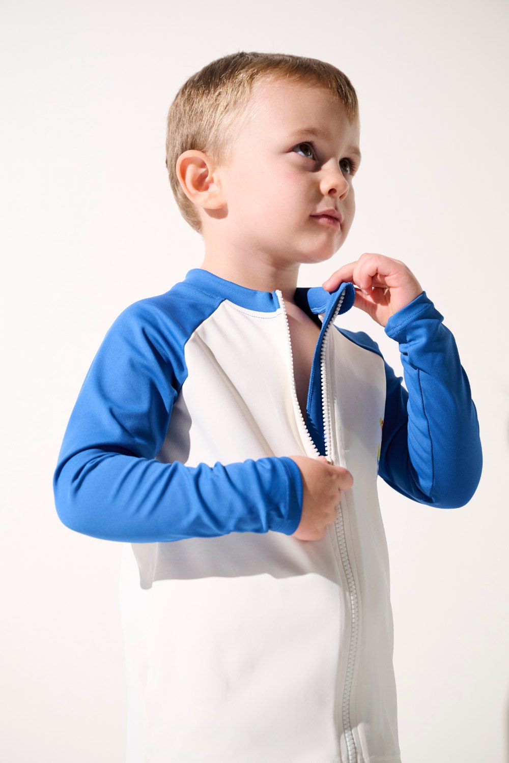 Veste de bain anti-UV - Fidji, enfant en lycra blanc et bleu, protection solaire UPF 50+ pour jeux à la plage.