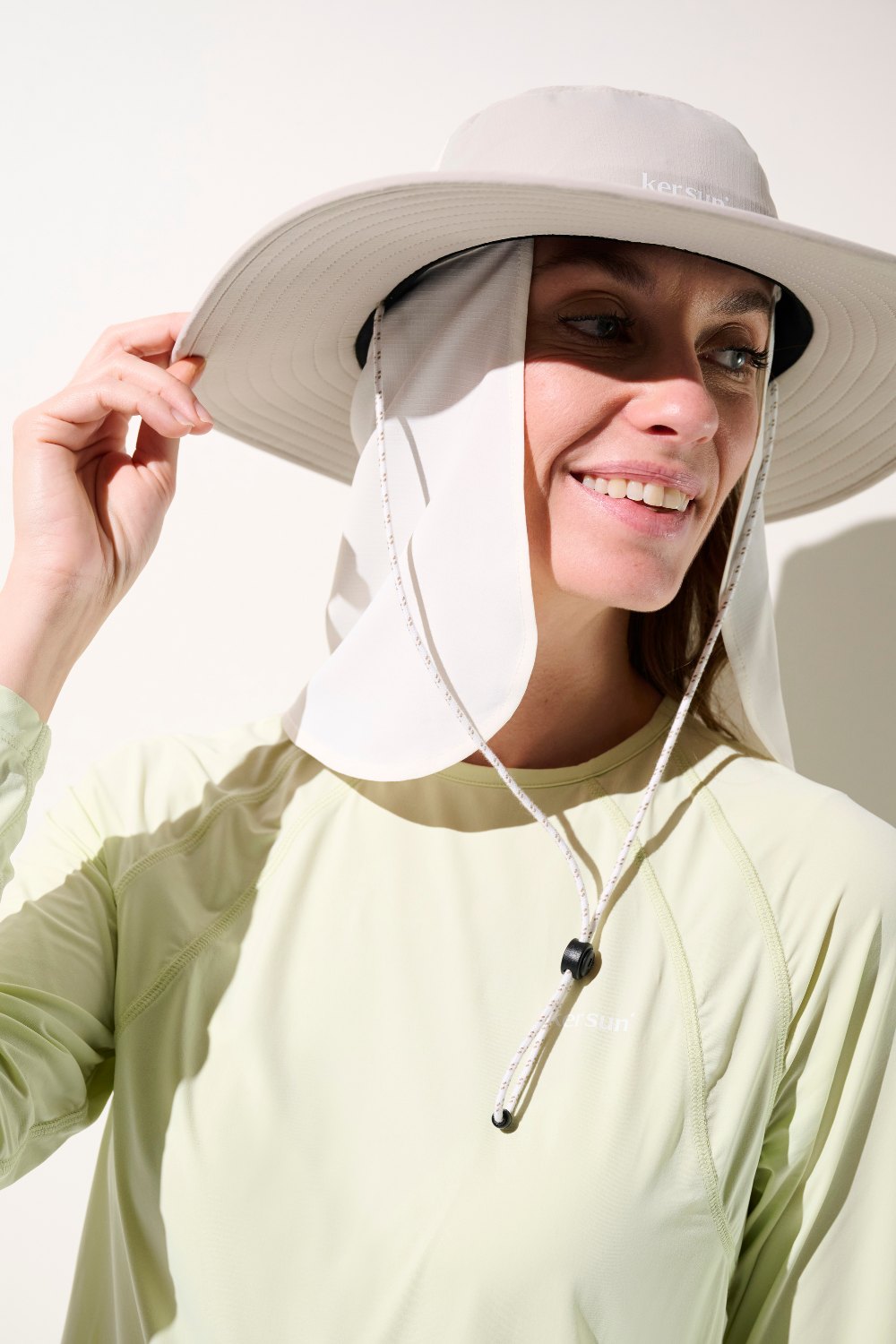 Femme souriante portant un cache-nuque anti-UV - Gobi et chapeau, idéal pour une protection solaire UPF 50+.